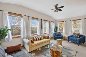 a living room with a couch and chairs and windows at River Access Cabin with Hot Tub, Fire Pit, & WiFi! in Morton Grove