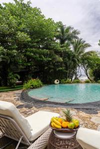 un bol de fruta sentado en una silla junto a una piscina en Ocho Artisan Bungalows, en Tamarindo