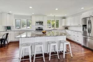 a kitchen with white cabinets and a large island with bar stools at Month to Month and Seasonal Luxury Lakefront 5 bed 5 5 bath Estate Home in Ingleside