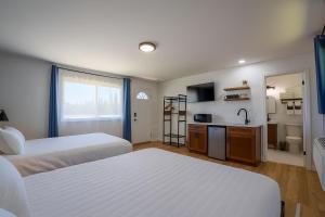 a bedroom with two beds and a kitchen with a sink at The Inn at Shady Pines in Gros Cap