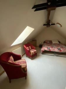 a attic room with a bed and two chairs at Maison Le 108 in Lamballe Armor