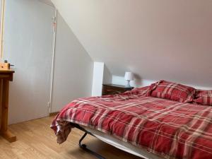 a bedroom with a bed with a red plaid blanket at Maison Le 108 in Lamballe Armor