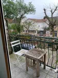 a wooden table and a chair on a balcony at Studio Spacieux au Grand Paris in Chennevières-sur-Marne