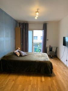 a bedroom with a bed and a large window at Studio Spacieux au Grand Paris in Chennevières-sur-Marne