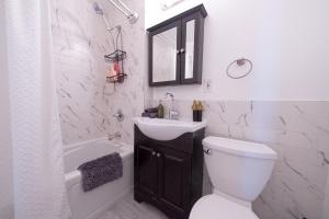 a white bathroom with a sink and a toilet at Sunlit 2BR Central Park North elevator & laundry in New York +55 photos