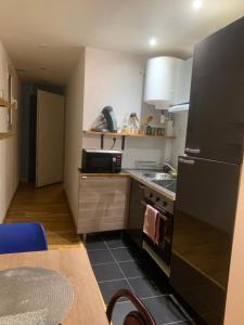 a kitchen with a black refrigerator and a sink at Studio Spacieux au Grand Paris in Chennevières-sur-Marne