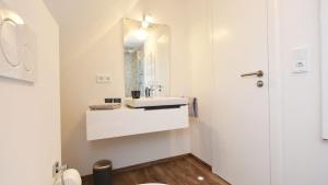 a white bathroom with a sink and a mirror at Exklusive Reetdach-Villa Ostseefrische in Lobbe +21 photos