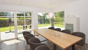 a dining room with a wooden table and chairs at Exklusive Reetdach-Villa Ostseefrische in Lobbe