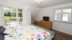 a bedroom with a bed and a tv and a window at Exklusive Reetdach-Villa Ostseefrische in Lobbe