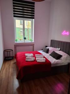 a bedroom with a red bed with towels on it at Apartament Love on 5 - Miłość na 5 in Legnica