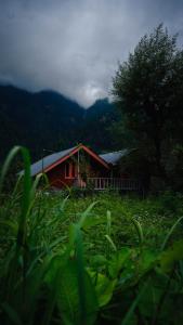 a red house in the middle of a field at Selah by soho house in Jibhi