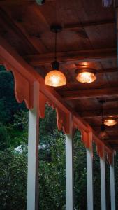 three lights on a wooden ceiling with a porch at Selah by soho house in Jibhi