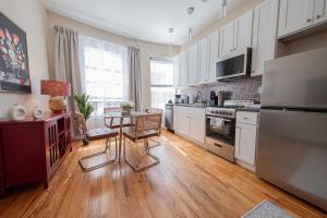 a kitchen with white cabinets and a table in it at Sunlit 2BR Central Park North elevator & laundry in New York