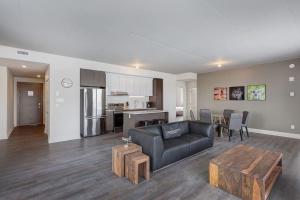 ein Wohnzimmer mit einer schwarzen Couch und einer Küche in der Unterkunft Corporate Stays Equinoxe 3 Bedrooms in Chomedey