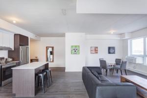 eine Küche und ein Wohnzimmer mit einer Couch und einem Tisch in der Unterkunft Corporate Stays Equinoxe 2 Bedroom in Chomedey + 13 Fotos