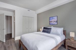 ein weißes Schlafzimmer mit einem großen Bett und einem Nachttisch in der Unterkunft Corporate Stays Equinoxe 1 Bedroom in Chomedey + 13 Fotos