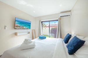 a bedroom with a white bed with blue pillows and a window at Palm Beach Sea La Vie Suites in Palm-Eagle Beach +179 photos