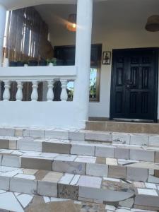 a house with white stairs and a black door at Beach house villa in Kokrobite