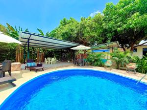 a large swimming pool with chairs and umbrellas at Villa Tranquila - Paraíso Privado con Piscina y Amplios Espacios Naturales con Casa Campestre in Ricaurte