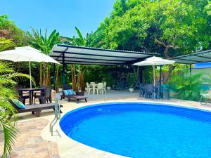 a swimming pool with umbrellas and chairs and a patio at Villa Tranquila - Paraíso Privado con Piscina y Amplios Espacios Naturales con Casa Campestre in Ricaurte