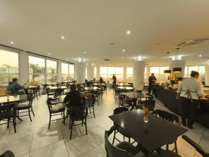 a restaurant with tables and people sitting at tables at Favorita Golden Hotel e Eventos in São José