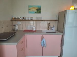 a kitchen with pink cabinets and a white refrigerator at מעיינות האהבה in Reshafim