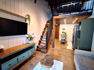 a living room with a television and a staircase at Loft Girassol in Palhoça