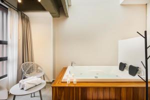 a bathroom with a bath tub and a chair at Hotel Attic 33 in Medellín