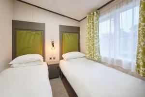 two beds in a room with a window at Happy Days Lodge with Hot Tub in York