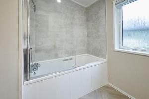a white bath tub in a bathroom with a window at Happy Days Lodge with Hot Tub in York +29 photos