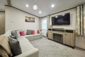 a living room with a couch and a flat screen tv at Happy Days Lodge with Hot Tub in York