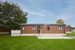 a small house in a yard with a green lawn at Happy Days Lodge with Hot Tub in York