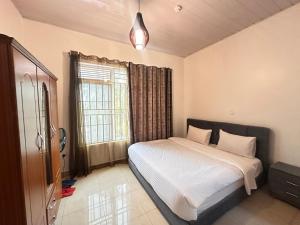 ein Schlafzimmer mit einem Bett und einem Fenster in der Unterkunft EASY KIGALI STAY Apartment in Kigali