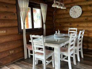 ミート・ポッド・ドゥンビエロムにあるZrub EMMAのダイニングテーブルと椅子、そして壁に掛けられた時計