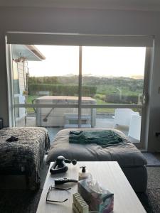 1 Schlafzimmer mit 2 Betten, einem Tisch und einem großen Fenster in der Unterkunft Peaceful retreat in big sky country, near beach in Mangawhai