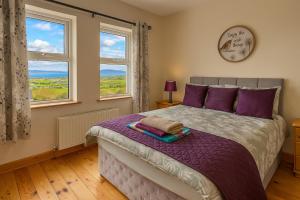 - une chambre avec un lit doté de draps violets et de fenêtres dans l'établissement Heather View Cottage, à Carrigart