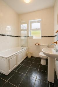 a bathroom with a tub and a toilet and a sink at 4 Bedroom House By Travel Lets Holiday Homes Carrigart With Sea View in Carrigart +25 photos