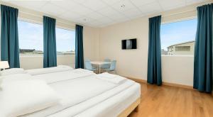 a bedroom with two beds and a table and windows at T10 Self check-in Hotel in Hafnarfjördur