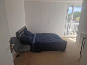 a bedroom with a bed and a chair and a window at Proche rocade sud in Rennes