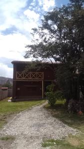 un edificio marrone con un albero accanto a una strada sterrata di Casa tarawasy hostel a Urubamba
