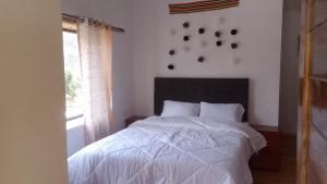 a bedroom with a white bed and a window at Casa tarawasy hostel in Urubamba