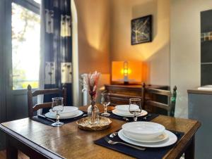 a wooden table with plates and wine glasses on it at T2 élégant & confortable, balcon - Amiens centre in La Celle-sous-Gouzon +7 photos
