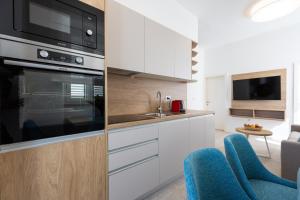 a kitchen with white cabinets and blue chairs at Apartments Cassia in Mali Lošinj +31 photos