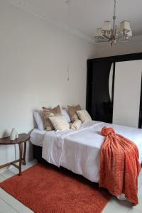 a bedroom with a large white bed with a red rug at The Acacia Apartment in Lusaka