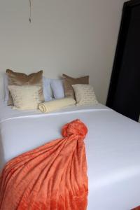 a white bed with an orange blanket on it at The Acacia Apartment in Lusaka