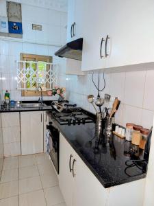 a kitchen with white cabinets and a black counter top at The Acacia Apartment in Lusaka +5 photos
