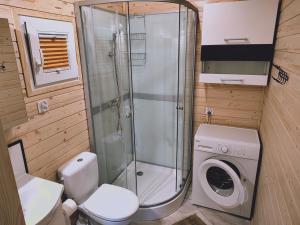a bathroom with a shower and a washing machine at Domki Przydwórz in Przydwórz