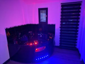 een donkere kamer met een bad met verlichting bij Loveroom Montargis in Montargis
