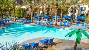a swimming pool with blue chairs and blue umbrellas at LV026 Secluded Downstairs Legacy Villas Studio in La Quinta
