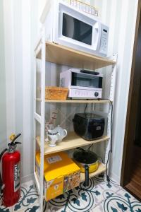 ein Küchenregal mit einer Mikrowelle und anderen Geräten in der Unterkunft G-Style 405 - Vacation STAY 20485 in Shimo-mizo + 21 Fotos